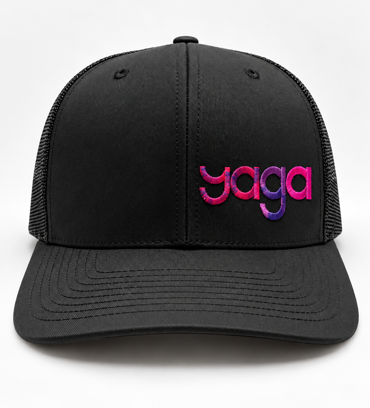 Black YAGA Signature Gradient Trucker Hat with pink and purple logo embroidery on the front panel.